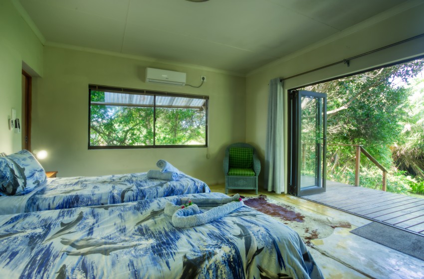 Bedroom with open stacker doors at Baleia Azul 26 in Ponta Mamoli