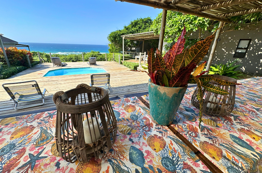 dining table with pool in the background at Baleia Azul 11 in Ponta Mamoli